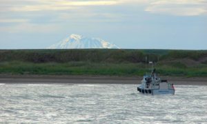 A boat on water in Alaska's Bristol Bay. There are mountains in the distance.